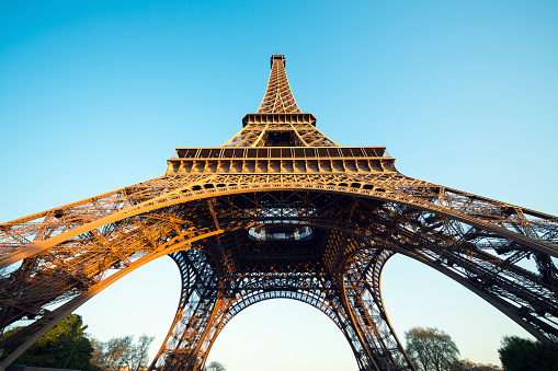 Low angle view of Eiffel tower in Paris, illuminated by the morning sunlight.