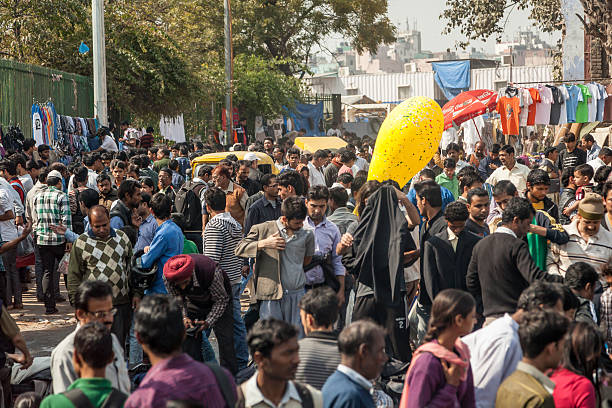 Old Delhi street scene where Indian people can be seen walking around. Street vendors are selling clothing.