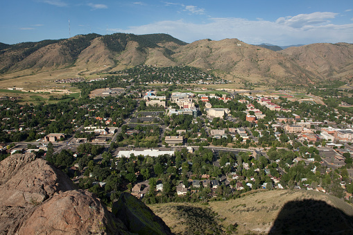 The shadow of Castle Rock stretches towards the downtown buildings of Golden and the Colorado School of Mines campus with the Rocky Mountains, Lookout Mountain and the Mines \
