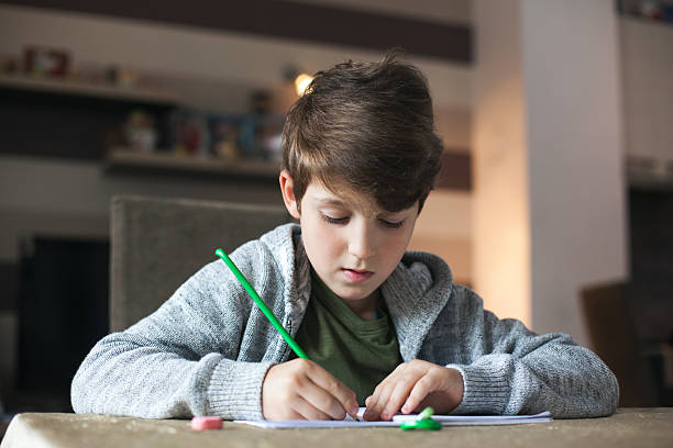istock Young boy sitting at the table doing his school homework. 530002630
