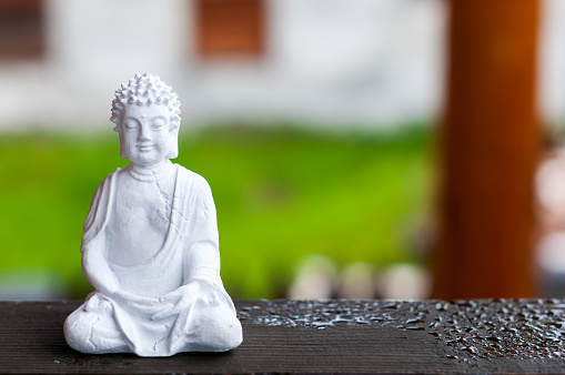 Ceramic Zen Buddha Statue Meditating with Blurred Texture Background. Yoga concept.