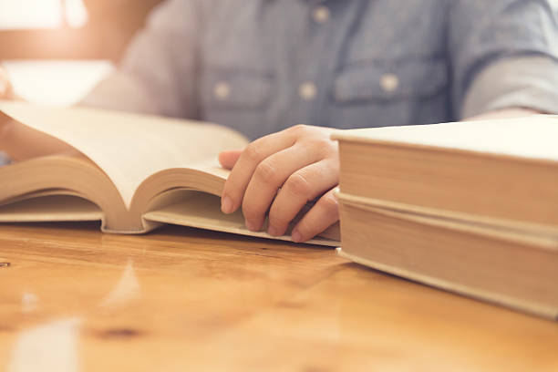 istock woman's hand reading book on wooden table 530003630