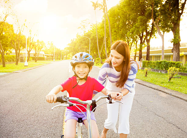 feliz pouco de menina com a mãe prática bicicleta de equitação - helmet bicycle little girls child imagens e fotografias de stock