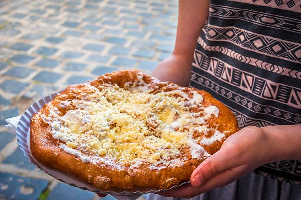 Langos with cheese and sour cream Lángos is a Hungarian food speciality. Langos is a dough made of water or milk and flour, with a dash of sugar and salt and fried in oil. hungarian culture stock pictures, royalty-free photos & images