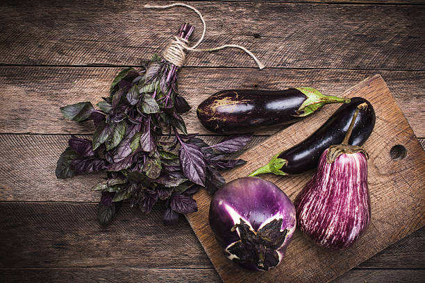 istock Aubergines and basil on chopping board in rustic style 530006387
