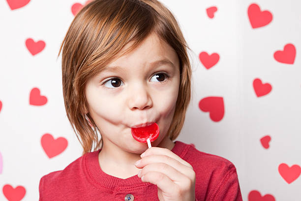 young boy 食べるヴァレンティーヌ棒付きキャンディ - child valentines day candy eating ストックフォトと画像