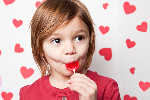 A 3 year old boy enjoying a Valentine lollipop.