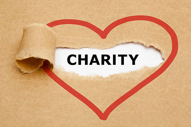 Charity Torn Paper Charity appearing behind torn brown paper. contributor stock pictures, royalty-free photos & images