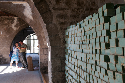 Aleppo, Syria - June 28, 2010: A Syrian man and woman stand in an old building where bars of traditionally-made soap is stacked in Aleppo, Syria.
