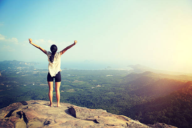 istock young woman open arms  at mountain peak cliff 530007558