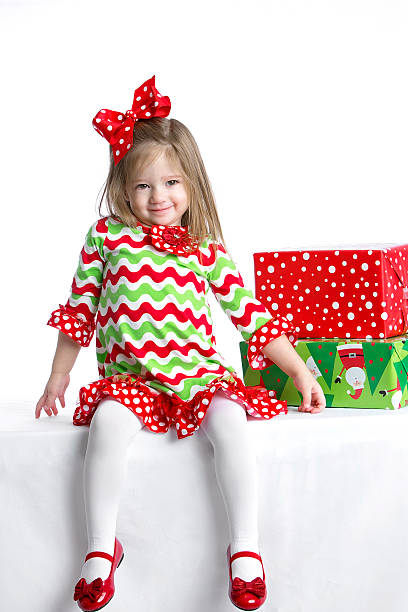 Cute little girl in colorful Christmas dress with gifts stock photo