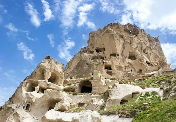 Uchisar in Cappadocia, Turkey. Cappadocia; also Capadocia; Turkish: Kapadokya is a historical region in Central Anatolia, largely in the Nevsehir, Kayseri, Aksaray, and Nigde Provinces in Turkey. The area is a popular tourist destination, as it has many areas with unique geological, historic, and cultural features. Touristic Cappadocia includes 4 cities: Nevsehir, Kayseri, Aksaray and Nigde. The most important towns and destinations in Cappadocia are Urgup, Goreme, Ihlara Valley, Selime, Guzelyurt, Uchisar, Avanos and Zelve. Among the underground cities worth seeing are Derinkuyu, Kaymakli, Gaziemir and Ozkanak. The best historic mansions and cave houses for tourist stays are in Urgup, Goreme, Guzelyurt and Uchisar. Hot-air ballooning is very popular in Cappadocia and is available in Goreme. Trekking is enjoyed in Ihlara Valley, Monastery Valley (Guzelyurt), Urgup and Goreme. The rocks of Cappadocia near Goreme eroded into hundreds of spectacular pillars and minaret-like forms. Vertical composition. Outdoor shot.