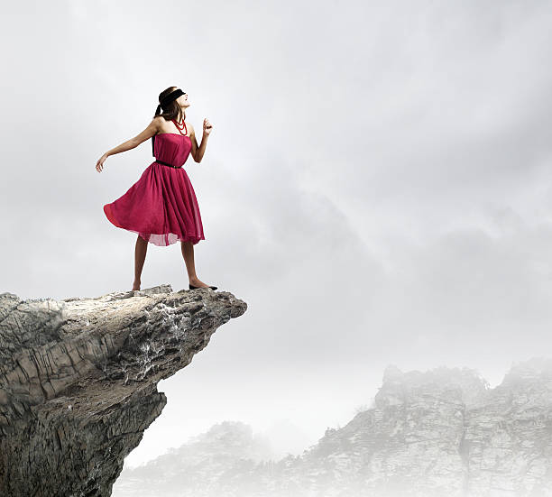 Woman in blindfold Woman in red dress standing on edge of rock red blindfold stock pictures, royalty-free photos & images