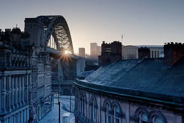 The Quayside at Newcastle upon Tyne and Gateshead photographed as the sun rises behind the Tyne bridge during the morning.