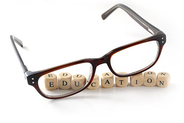 istock glasses and education message written in wooden blocks, isolated 530048767
