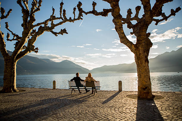 istock People on bench watching lake at sunset 530088641
