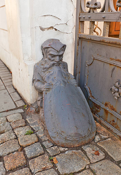 Old wheel guard (bollard) in the shape of dwarf with a shield near historic house (XIX c.) in Lodz, Poland