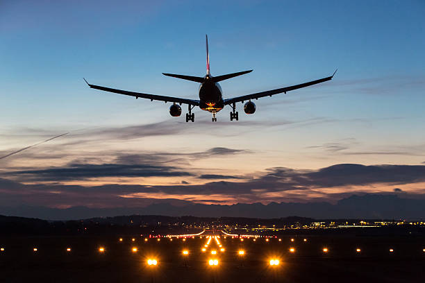 Landing airplane Photo of an airplane just before landing in the early morning. Runway lights can be seen in the foreground. commercial airplane stock pictures, royalty-free photos & images