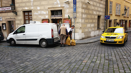 Prague, Czech Republic - September 26, 2014:  Distribution driver is delivering two mesh sacks of yellow potatoes to customer in Old Town Prague