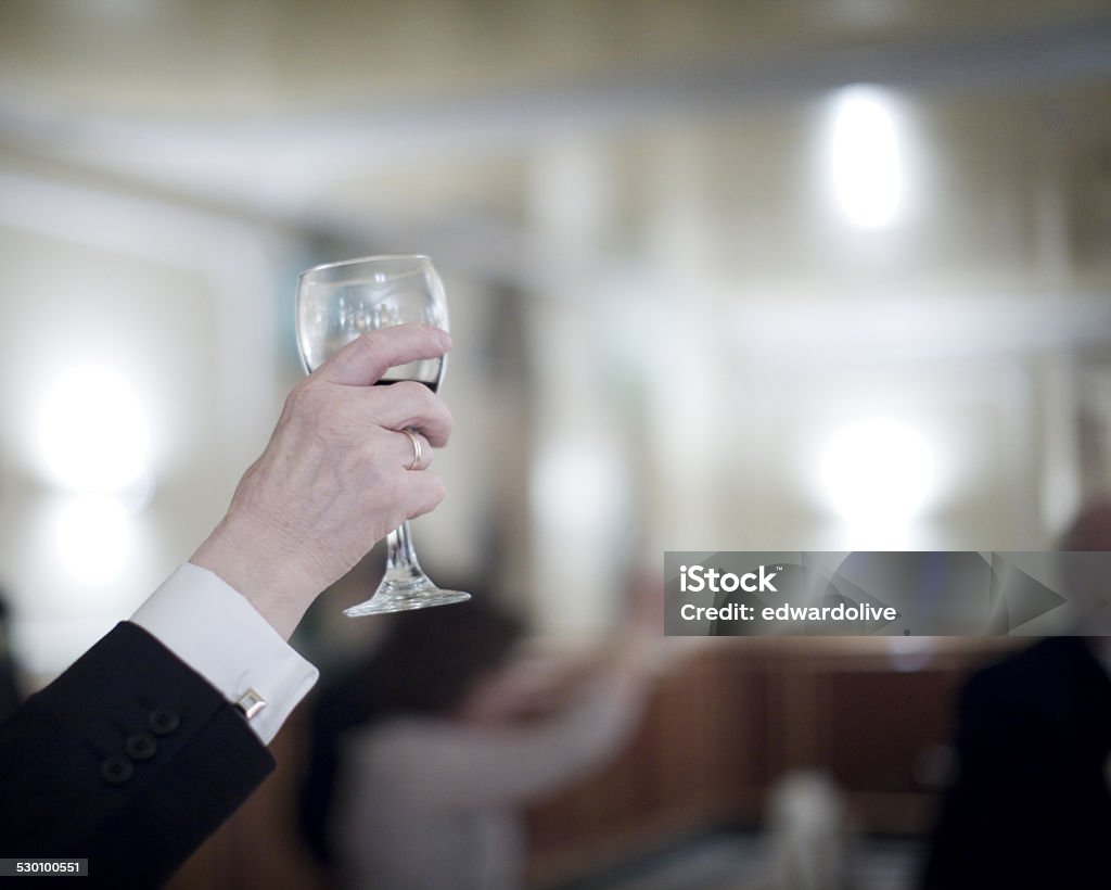 Man in wedding party and glass of red wine Color artistic digital rectangular horizontal photo of hand of man in dark suit and white shirt in wedding reception banquet marriage party holding  glass of red wine glass. Shallow depth of with background out of focus.  Adult Stock Photo
