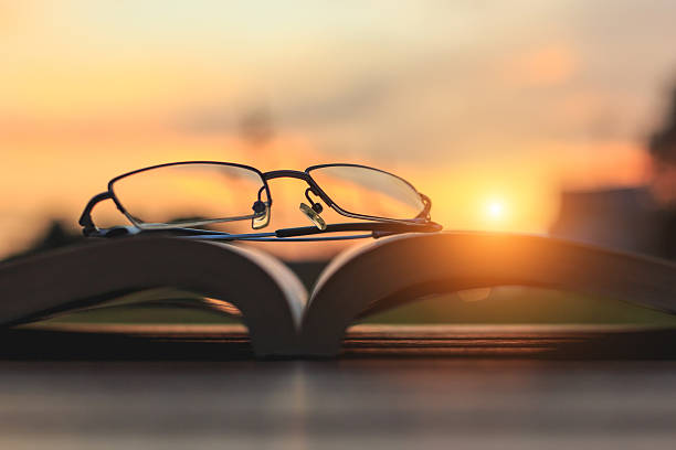 istock Close up glasses and book on table in sunset time 530100661