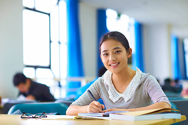 istock pretty asian college student smile at camera in library 530102863