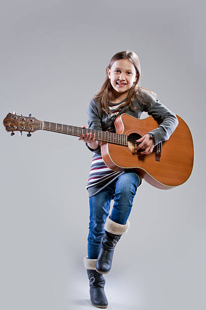istock little girl playing acoustic guitar 530103033