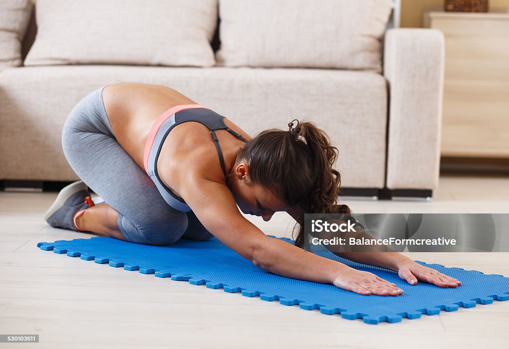 Attractive female doing exercise at home. Attractive female doing exercise in her living room.She stretching her back. Activity Stock Photo