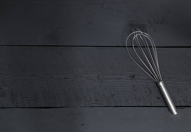 istock Whisk on a black wood as the background 530116859