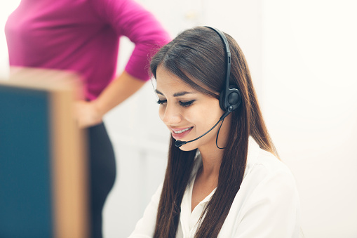 Portrait of an young positive woman with headset working at customer care call centar.