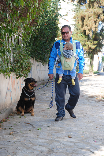 Single father on a daily walk with his 1 year old son and dog (rottweiler).
