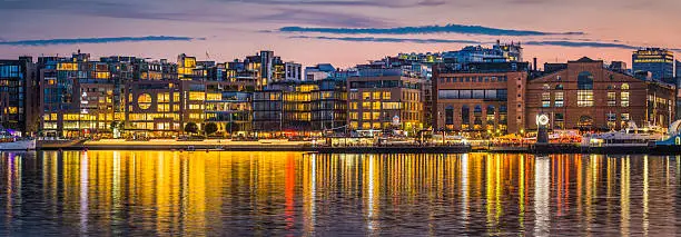 Panoramic view across the tranquil waters of Oslofjorden reflecting the busy bars and restaurants, modern apartment buildings and cultural centres of Aker Brygge, the popular waterfront redevelopment in the heart of downtown Oslo, Norway's vibrant capital city. ProPhoto RGB profile for maximum color fidelity and gamut.