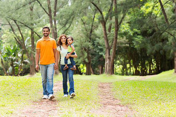 indian family going for a walk in forest happy young indian family going for a walk in forest indian man walking in park stock pictures, royalty-free photos & images