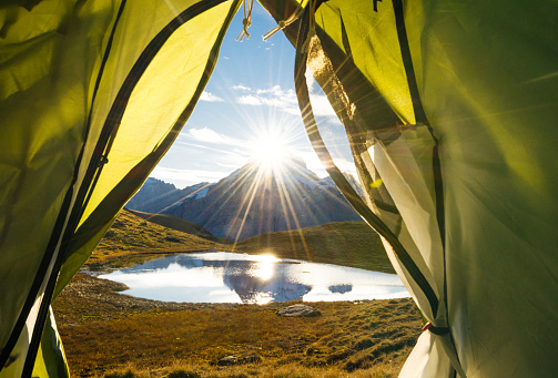 View out of a tent in the Bernese Oberland, a famous tourist spot in Switzerland. In the background are mountains and a small lake, close to the famous \