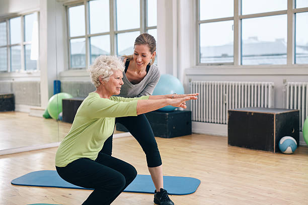 vieil femme de faire de l'exercice avec son entraîneur particulier - coach exercising instructor gym photos et images de collection