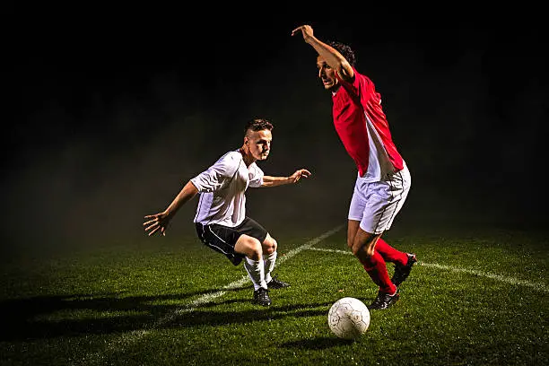 Two soccer players challenging for the ball, low angle view.