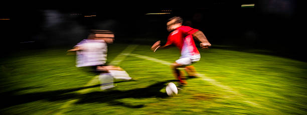 Two soccer players challenging for the ball, panoramic with blurred motion.