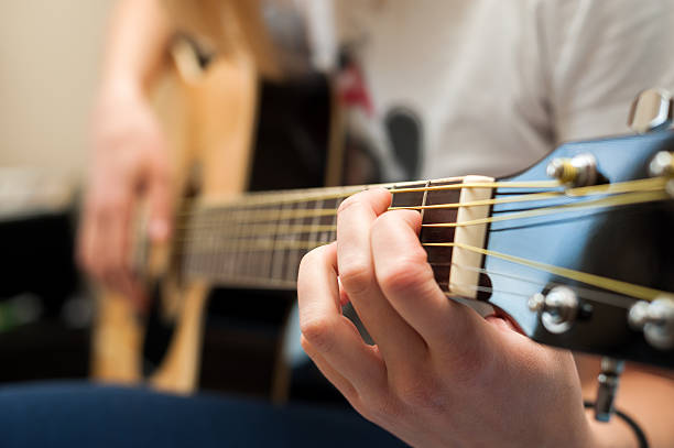 istock Student female practicing the guitar close-up with focus on hand 530160195