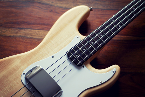 Berlin, Germany - November 06, 2014: Wooden Fender bass guitar shot on a wooden table in Berlin, Germany. The bass guitar has a natural finish.