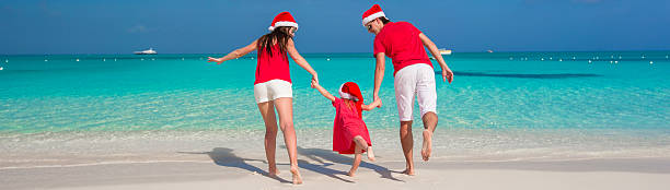 istock Happy family in Christmas Hats having fun on white beach 530184113