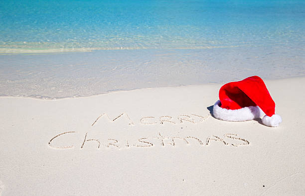istock Merry Christmas written on beach white sand with xmas hat 530184167