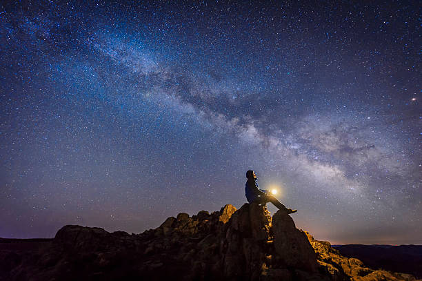 Man sitting under The Milky Way Galaxy Man sitting under The Milky Way Galaxy with light on his hands. star field photos stock pictures, royalty-free photos & images
