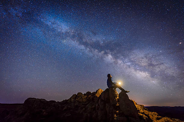 homem sentado sob a via láctea galáxia - exploração espacial - fotografias e filmes do acervo