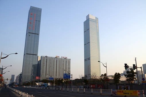 Wuxi, China - February 9, 2016: The Wuxi Maoye City-Marriott Hotel, height 304 mt. and The Wharf Times Square, height 339 mt, the tallest building in Wuxi, two super tall skyscrapers. In the background, people walking on the street.