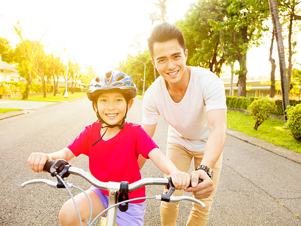 feliz pouco de menina com o pai prática bicicleta de equitação - helmet bicycle little girls child imagens e fotografias de stock