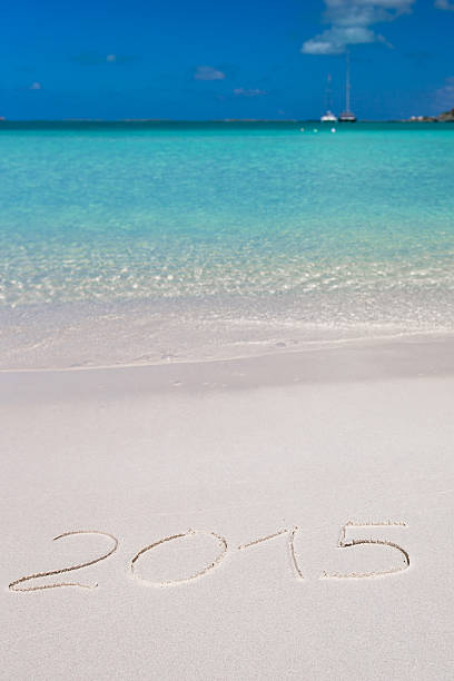 istock 2015 written on tropical beach white sand with xmas hat 530186661