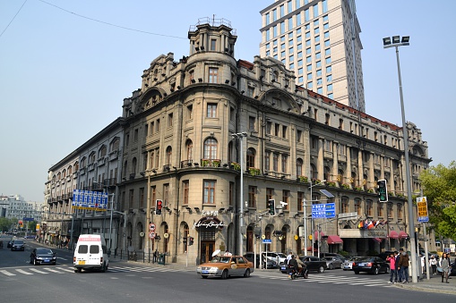 Shanghai, China - April 22, 2015: The Astor House Hotel,an historical hotel established in 1846 as Richards' Hotel and Restaurant on The Bund in Shanghai, is located near the confluence of the Huangpu River and the Suzhou Creek in the Hongkou District. People walking on the street. 