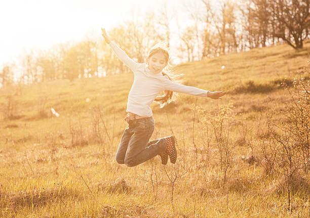 smiling little girl jumping on sunlight in countryside smiling little girl jumping on sunlight in countryside on a hill hot gilr stock pictures, royalty-free photos & images