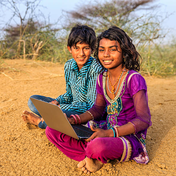 istock Happy Indian children using laptop, desert village, India 530192094