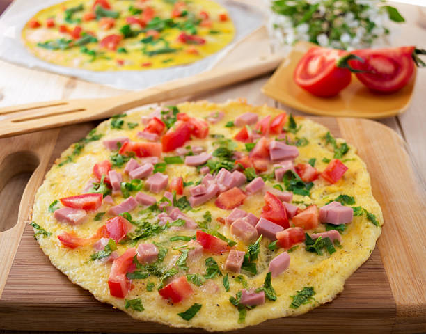 Omelette with vegetables on wooden background.